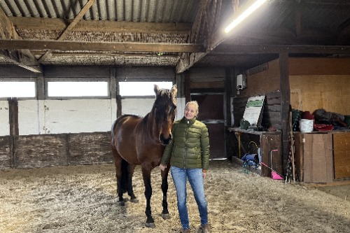 Marieke Herrenburg paardencoach met paard in paardenstal